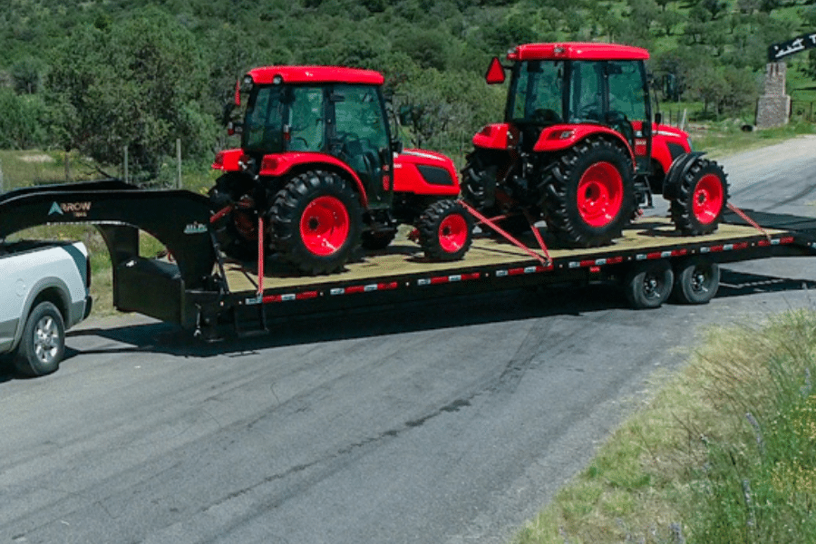 red tractors being hauled on gooseneck arrow trail trailer