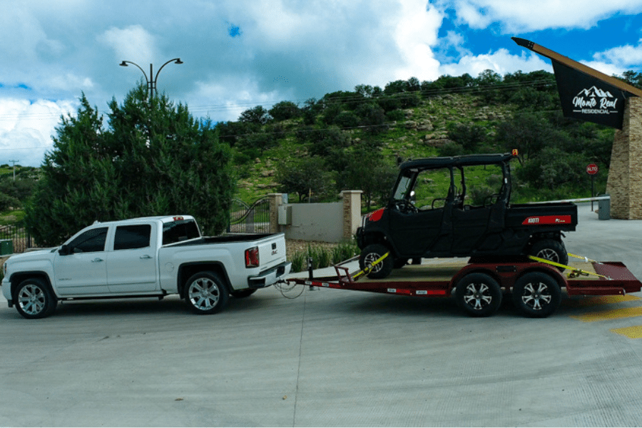 white truck hauling black golf cart on red car hauler trailer from Ohio