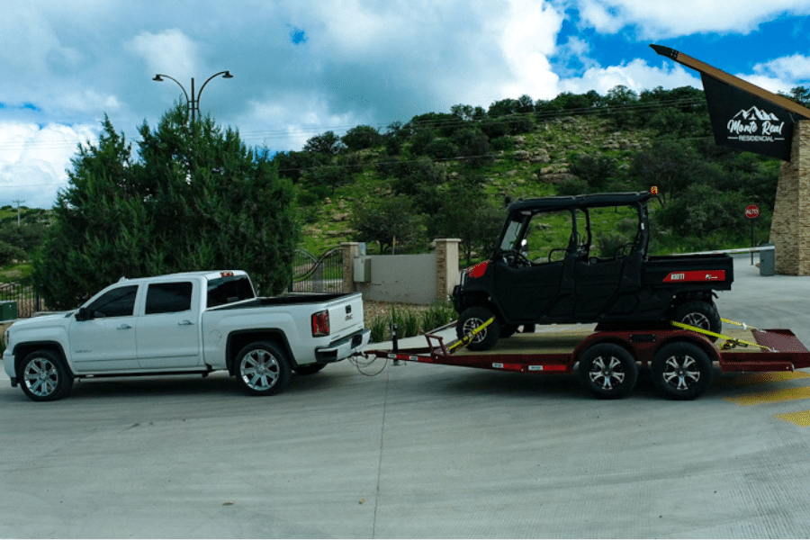 white truck with red trailer hauling black ATV